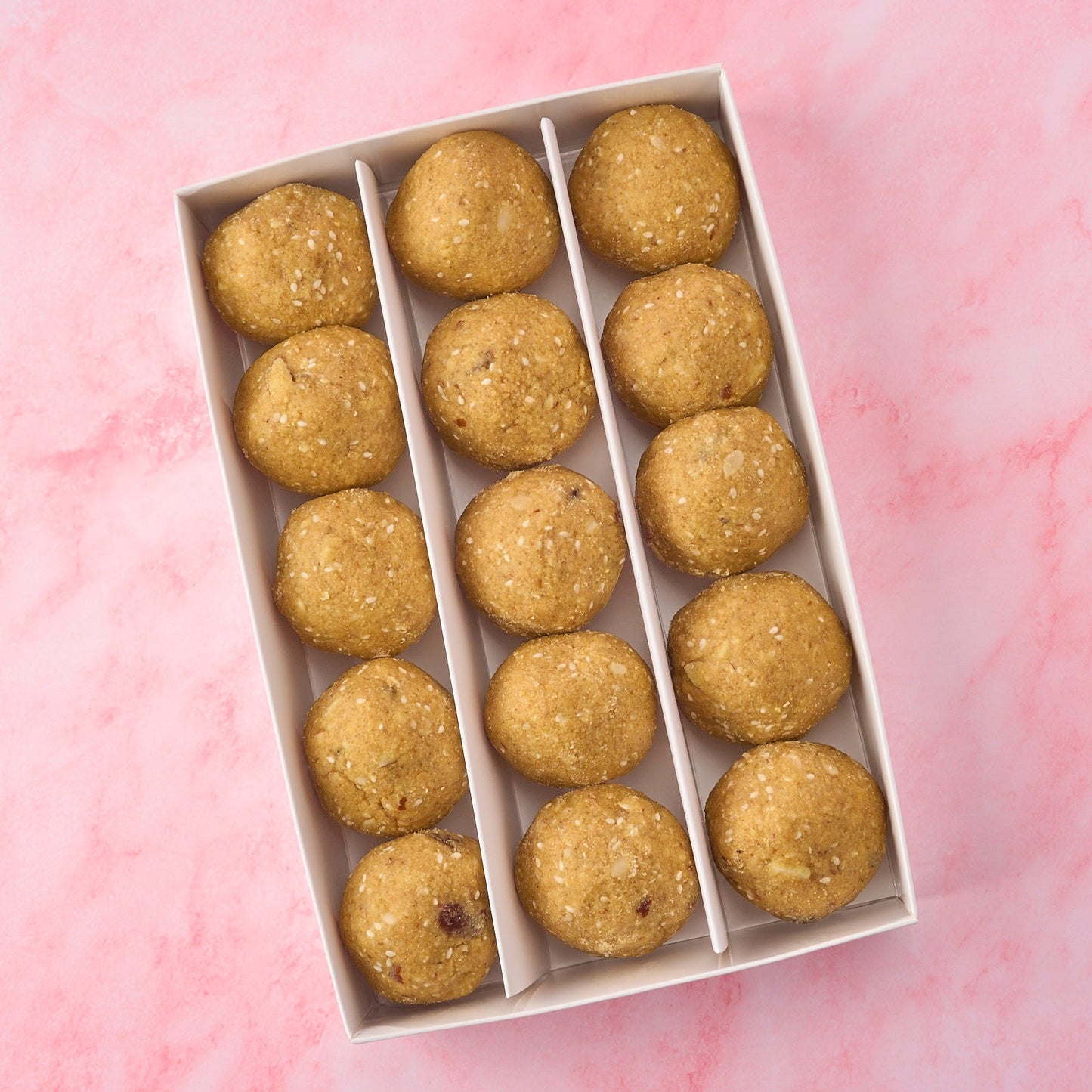 Large box of khoya dry fruit pinni arranged neatly in a traditional Punjabi pinni box