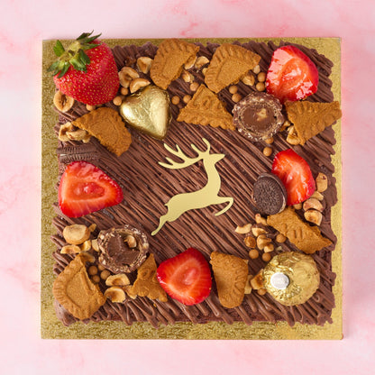Christmas Brownie Cake decorated with strawberries, Biscoff, nuts, Ferrero Rocher and a golden reindeer charm.
