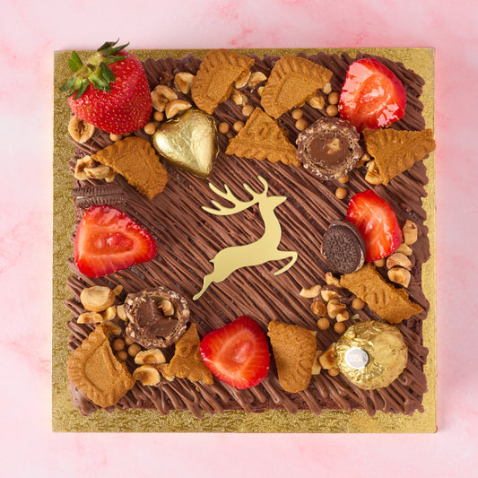 Christmas Brownie Cake decorated with strawberries, Biscoff, nuts, Ferrero Rocher and a golden reindeer charm.