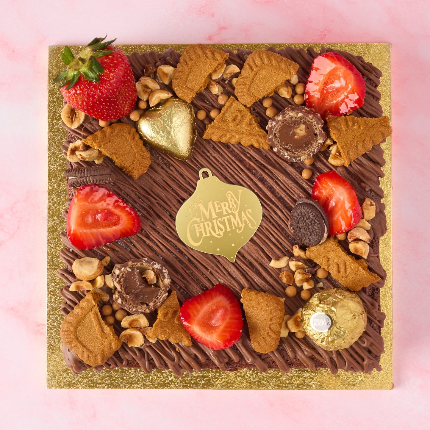 Christmas Brownie Cake in Sydney decorated with strawberries, Biscoff, nuts, Ferrero Rocher and a golden “Merry Christmas” ornament charm