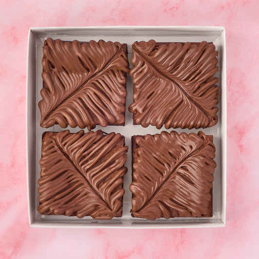 Chocolate brownie box with four eggless brownies topped with milk chocolate