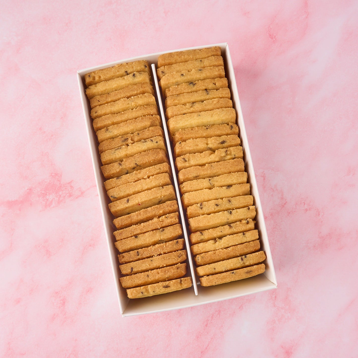 Open box of jeera biscuits showing neatly arranged eggless Indian savoury tea biscuits