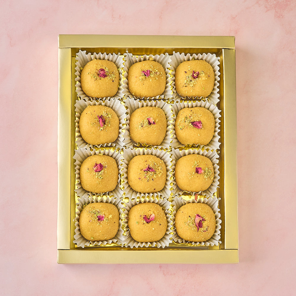 12 Besan Laddoos arranged in a gold-coloured tray inside gift box