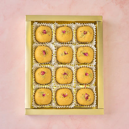 12 Besan Laddoos arranged in a gold-coloured tray inside gift box