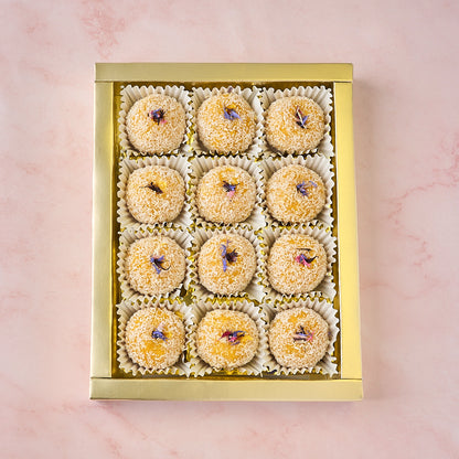 12 Mango Coconut Laddoos arranged in a gold-coloured tray in gift box