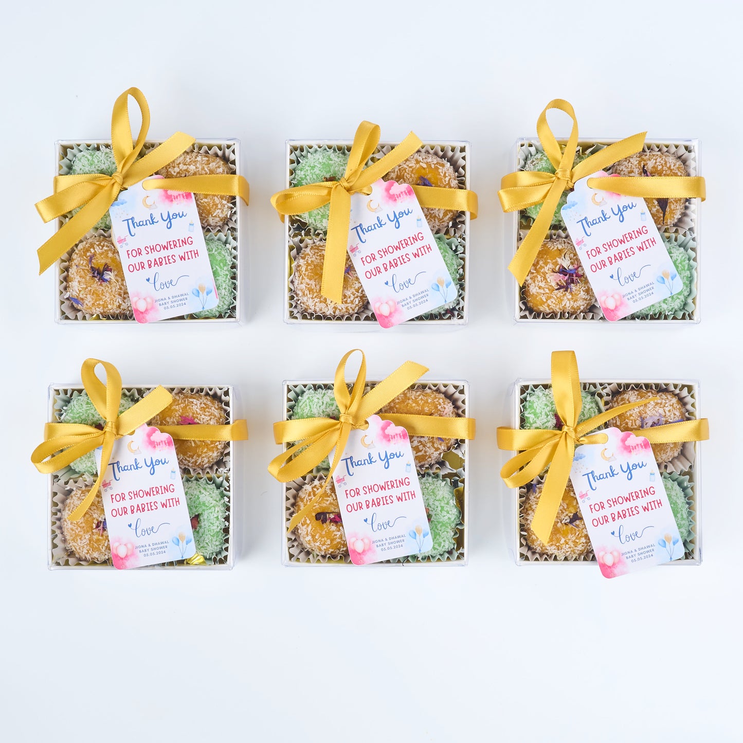 Multiple mango and rose gulkand coconut laddoo return gift boxes arranged for bulk guest distribution at weddings pooja functions and modern celebrations