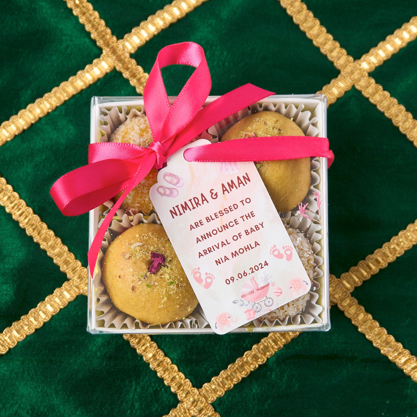 Top view of mango coconut and besan laddoo return gift box 4 pc arranged in transparent lid sweet box for guest gifting