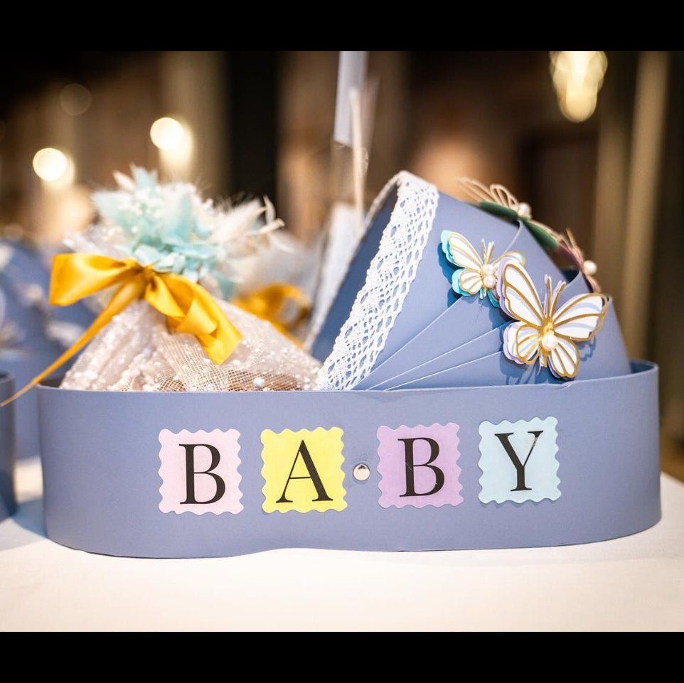 New baby bassinet gift hamper in blue basket with personalised card and eggless Pistachio Mawa Cake