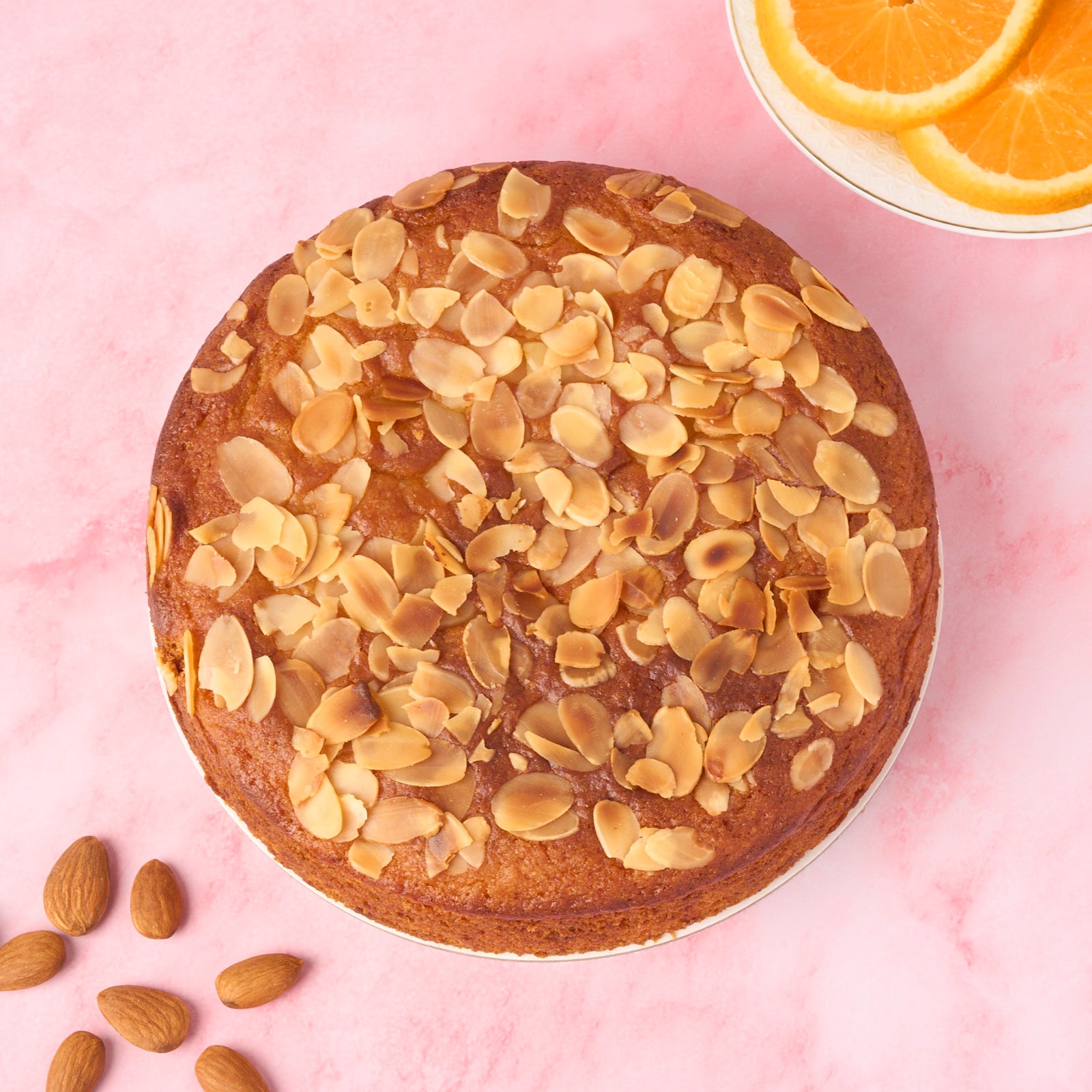 Orange Almond Cake topped with roasted almond flakes, top view.