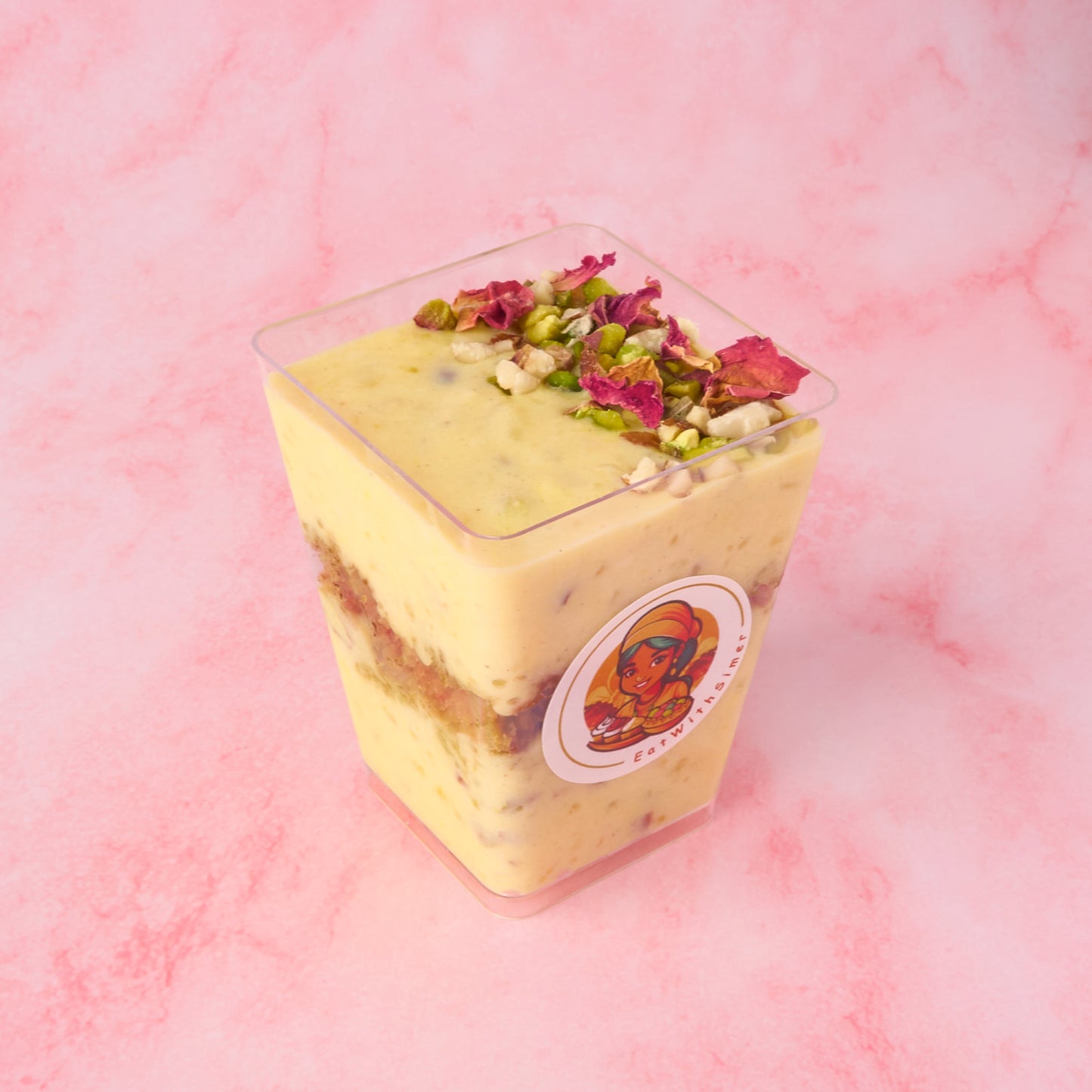 Angled view of Pistachio Kheer Trifle Cup with saffron kheer, pistachio cake crumble, almonds, cashews and organic rose petals