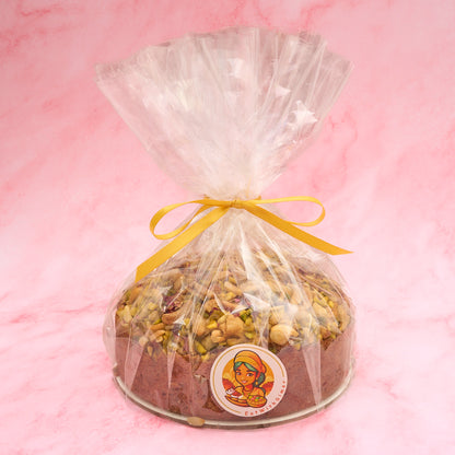 Eggless Pistachio Mawa Cake wrapped in clear gift packaging with ribbon