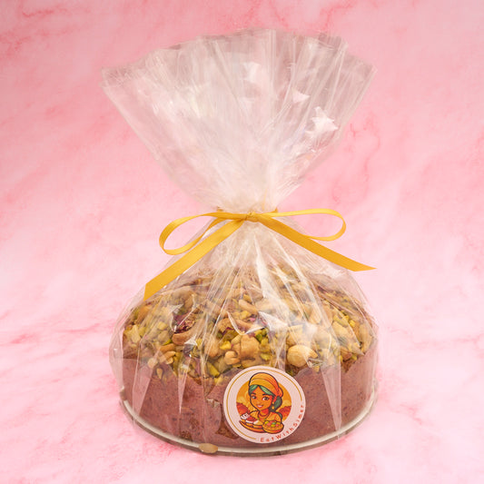 Eggless Pistachio Mawa Cake wrapped in clear gift packaging with ribbon
