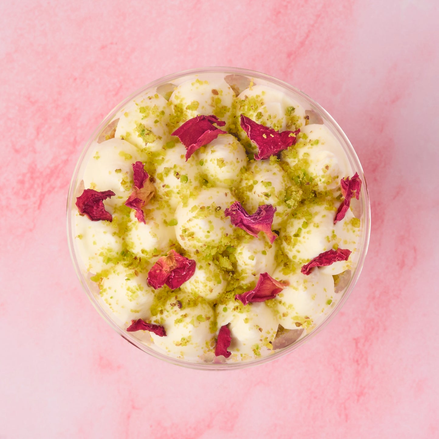 Top view of rasmalai pistachio trifle cups topped with crushed pistachio and dried rose petals, finished neatly for events and dessert tables