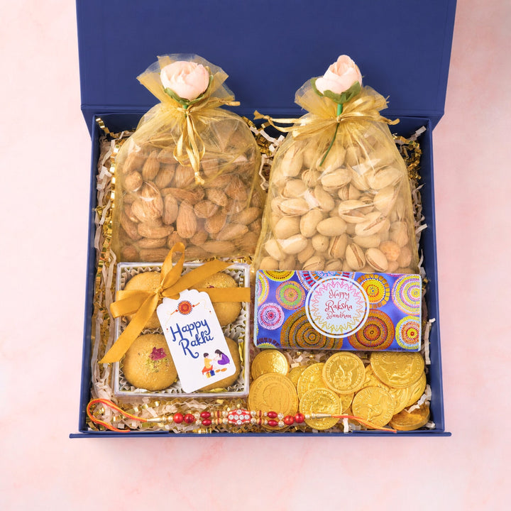 Open blue Rakhi gift hamper with Besan Laddoos, roasted almonds, pistachios, chocolates and Red & Gold Bead Rakhi