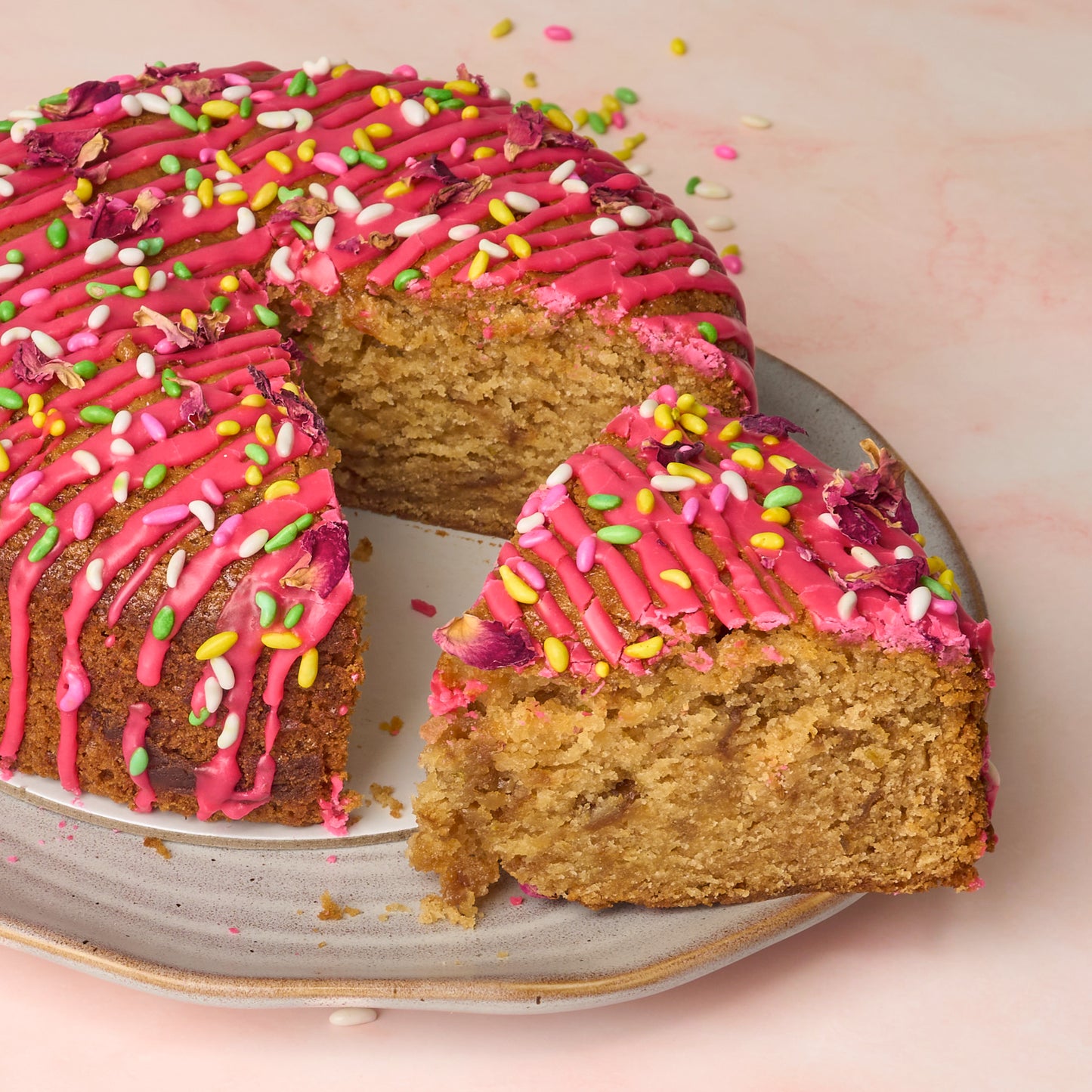 Slice of eggless rose gulkand cake showing soft, moist crumb and sprinkle-like candied fennel topping Sydney